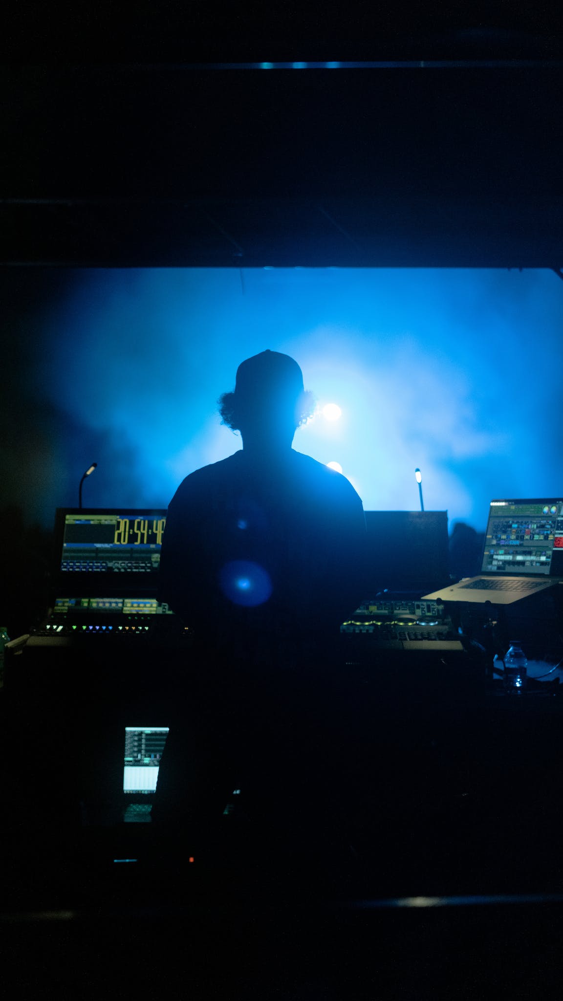 Back View of a DJ Standing Behind His Console in a Club 